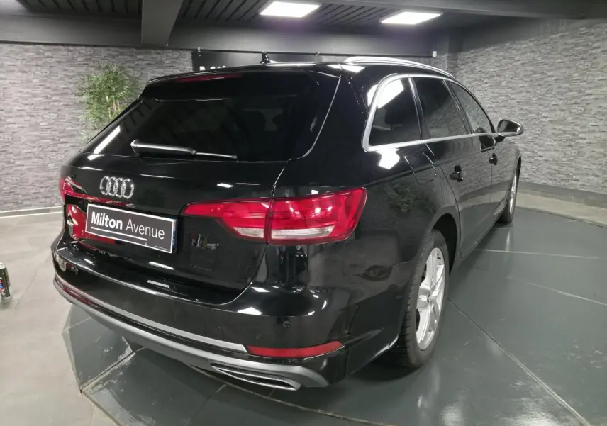 Audi A4 Avant noire vue 3/4 arrière droit, avec jantes aluminium 17 pouces et sorties d’échappement chromées.