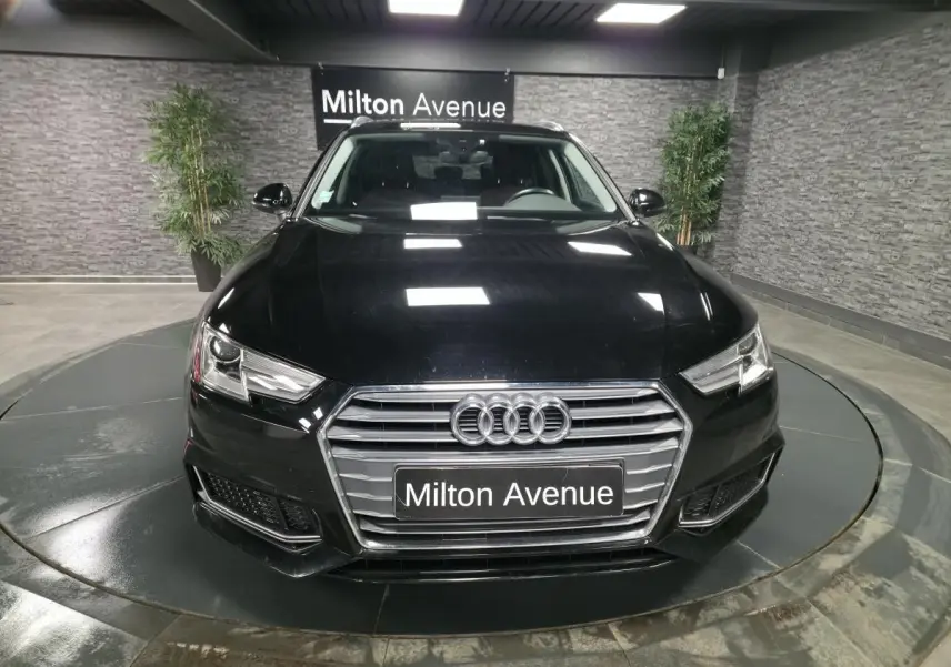 Vue avant d'une Audi A4 Avant noire 2019 avec calandre chromée et phares LED dans un showroom.