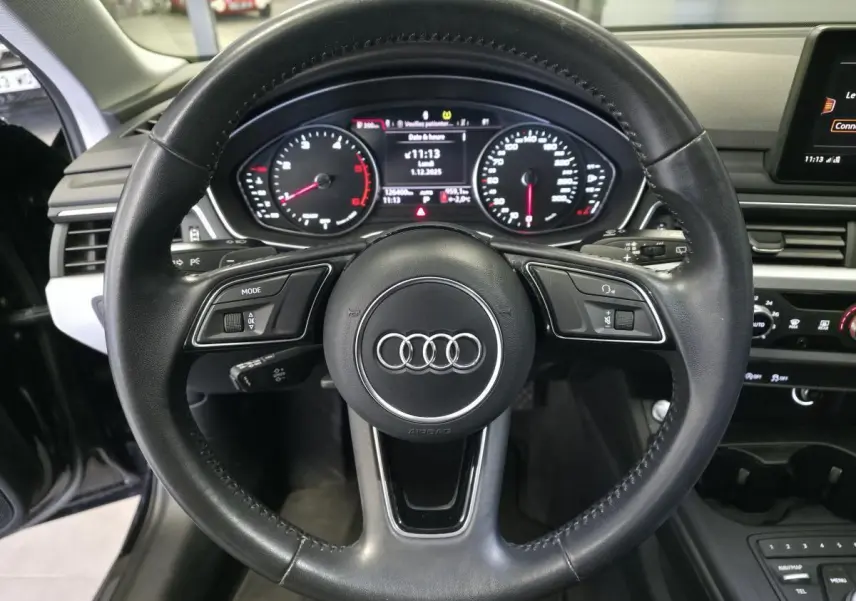 Vue intérieure centrée sur le volant noir de l'Audi A4 2019 avec tableau de bord numérique et commandes intégrées.