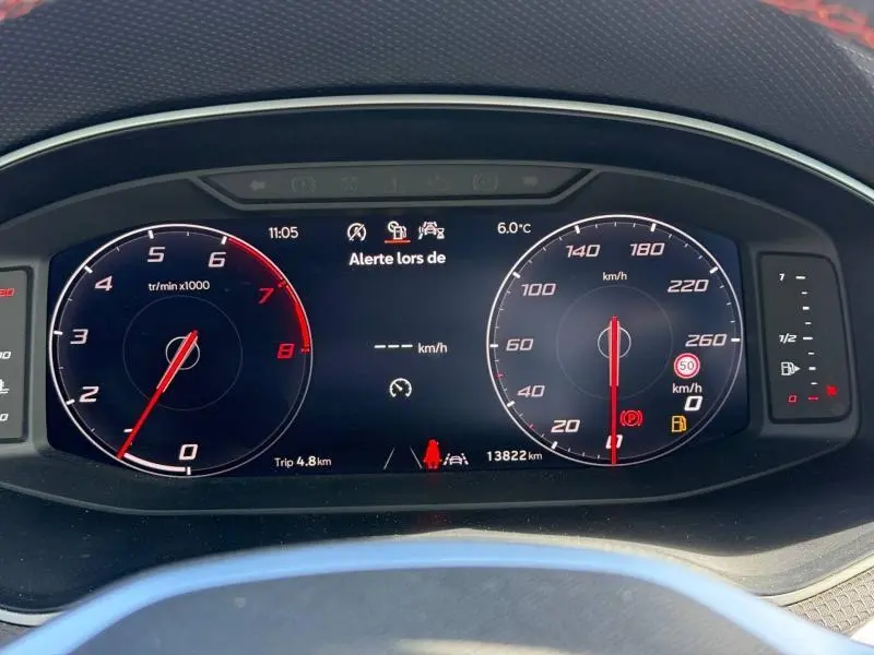 Tableau de bord numérique du SEAT Arona 1.0 TSI 115ch FR affichant compte-tours, vitesse et alertes, vue frontale rapprochée.