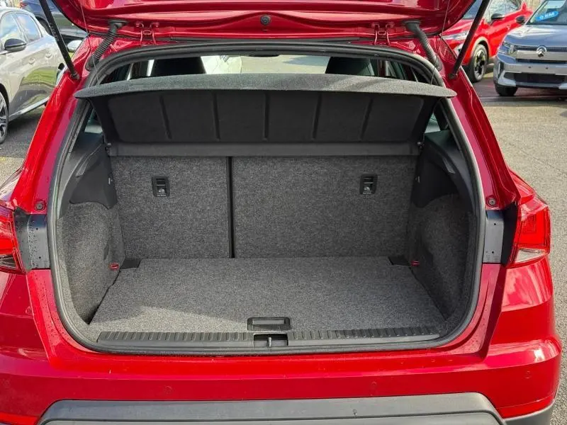 Coffre ouvert vu de l'arrière d'un SEAT Arona 2025 Rouge Désir avec toit Noir Minuit, montrant l'espace de rangement vide.