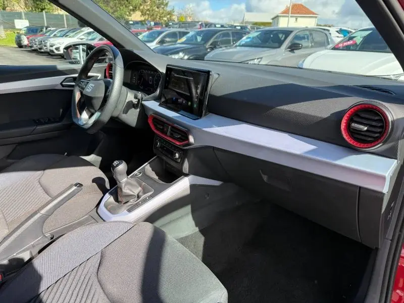 Vue intérieure côté conducteur du SEAT Arona 2025 avec détails rouges sur les aérateurs et console centrale.