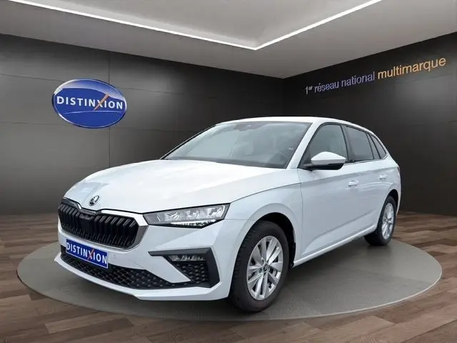 Vue 3/4 avant droite d'une Skoda Scala blanche exposée en showroom avec calandre noire et phares LED.