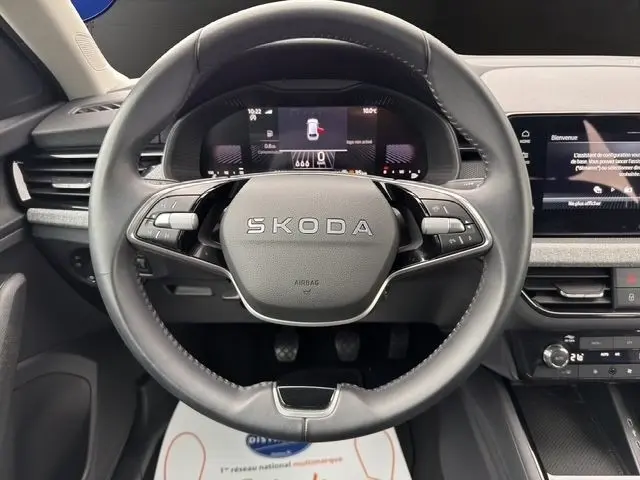 Vue rapprochée du volant cuir et alu d'une Skoda Scala blanche 2025, avec affichage numérique et écran tactile au tableau de bord.