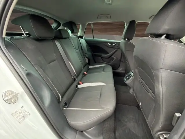 Vue intérieure arrière côté gauche de la Skoda Scala blanche 2025, montrant la banquette noire et les sièges avant.