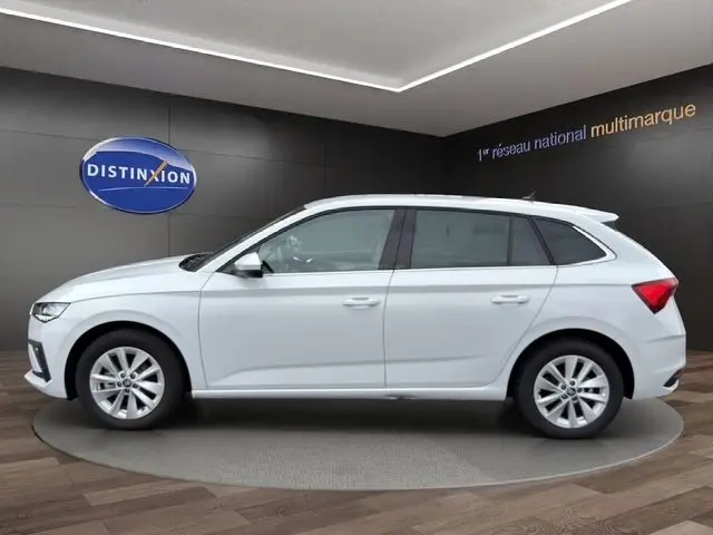 Vue latérale droite d'une Skoda Scala blanche 2025 en intérieur, avec jantes alliage et lignes épurées visibles.
