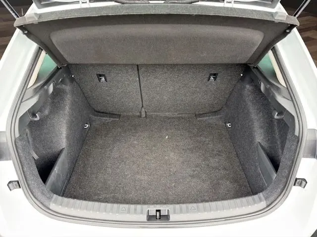 Vue plongeante sur le coffre ouvert d'une Skoda Scala blanche, montrant un espace de chargement vide et tapissé de moquette grise.