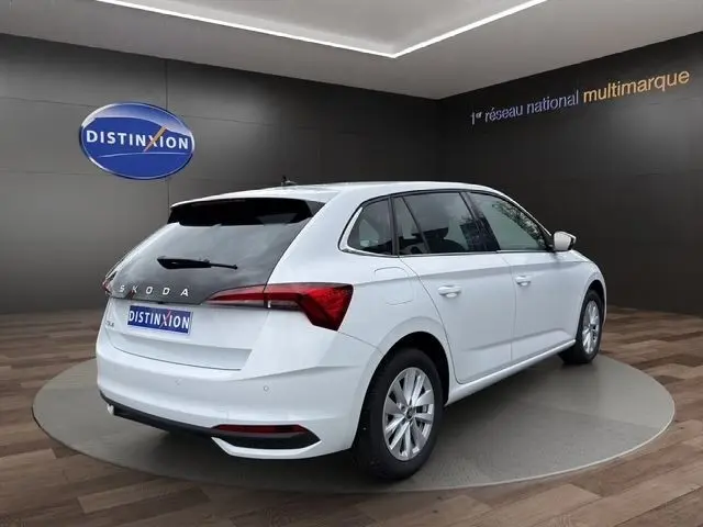 Vue 3/4 arrière droite d'une Skoda Scala blanche en intérieur, avec feux arrière LED et caméra de recul visible.