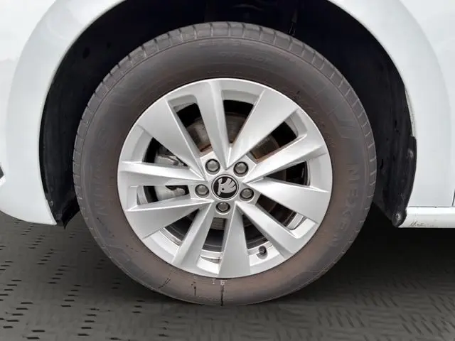 Gros plan sur la roue avant droite blanche d'une Skoda Scala 2025 avec jante alliage et logo central distinctif.