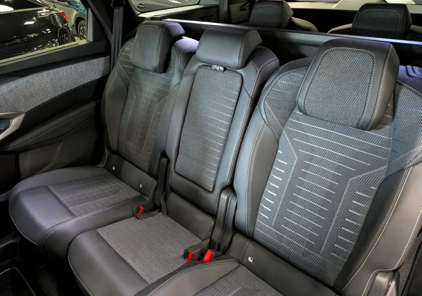 Vue intérieure sur les sièges arrière en tissu gris et cuir noir du Peugeot 5008 Hybrid 2025, avec appuie-têtes intégrés.