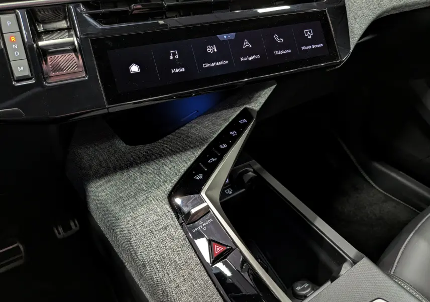 Vue rapprochée de la console centrale du Peugeot 5008 Hybrid 145 GT 2025 avec écran tactile et commandes tactiles sur tissu gris.