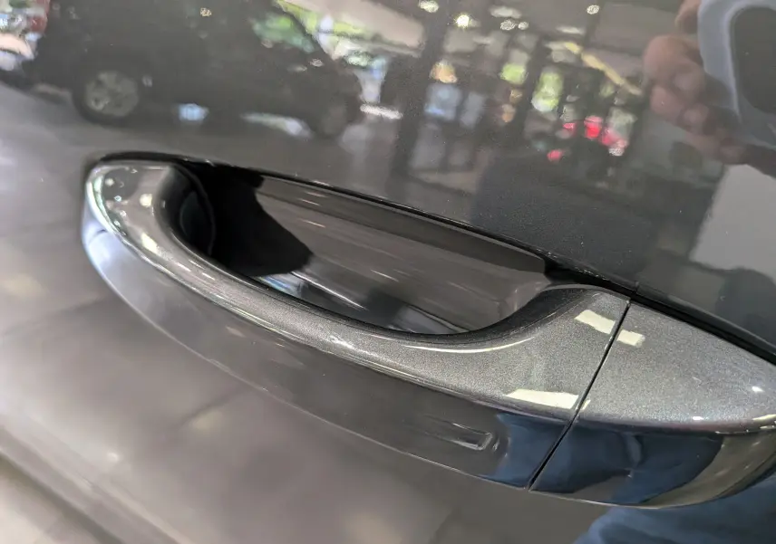 Poignée de porte avant droite gris titane du Peugeot 5008 Hybrid 145 CH e-DCS6 GT 2025 avec reflet intérieur showroom.