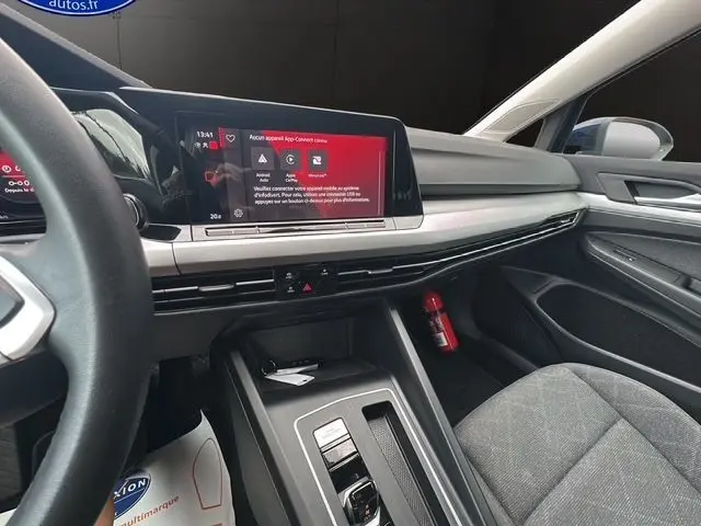 Intérieur noir de la Volkswagen Golf VIII 2023, vue du tableau de bord et console centrale avec écran tactile allumé.