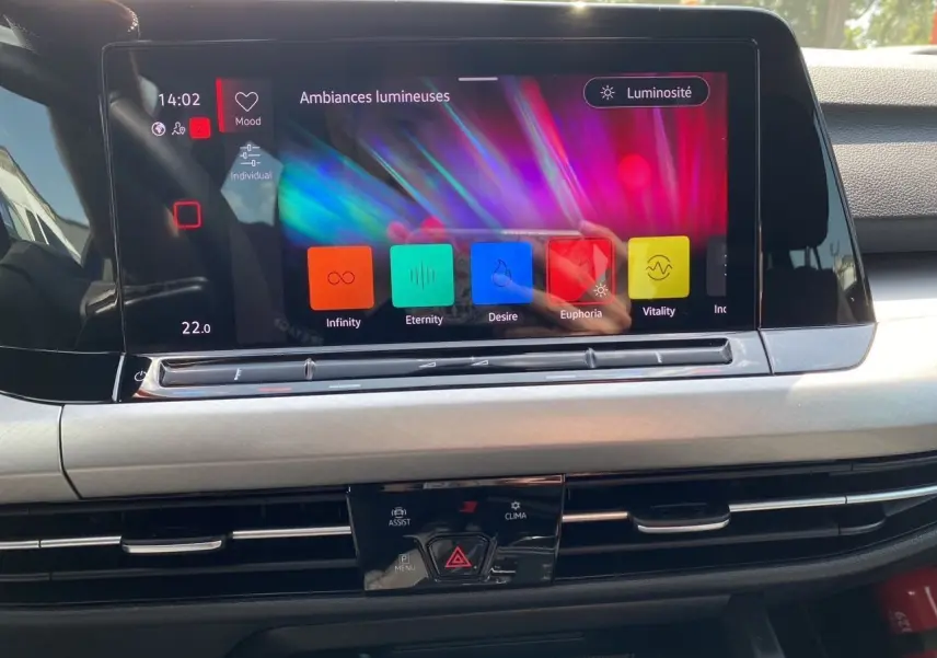 Écran tactile central de la Volkswagen Golf VIII bleu, affichant les ambiances lumineuses dans l'habitacle noir.