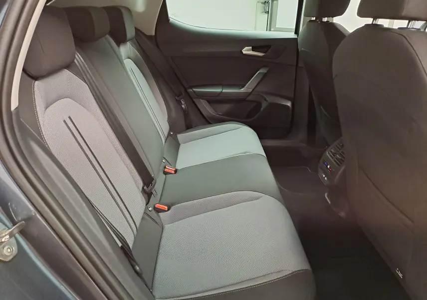 Vue intérieure côté gauche des sièges arrière gris clair et foncé du SEAT LEON 1.5 eTSI Hybrid 2025 avec portières ouvertes.