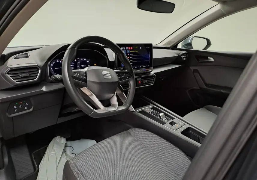 Vue intérieure côté conducteur du SEAT LEON 1.5 eTSI Hybrid 2025, avec tableau de bord numérique et écran tactile central.