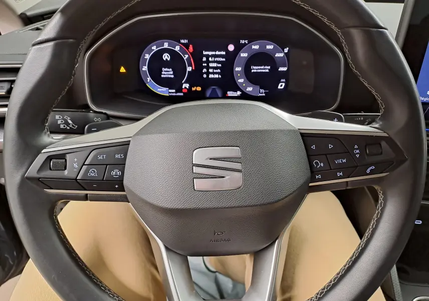 Vue rapprochée du volant multifonction d’une SEAT LEON 2025 avec tableau de bord numérique allumé.