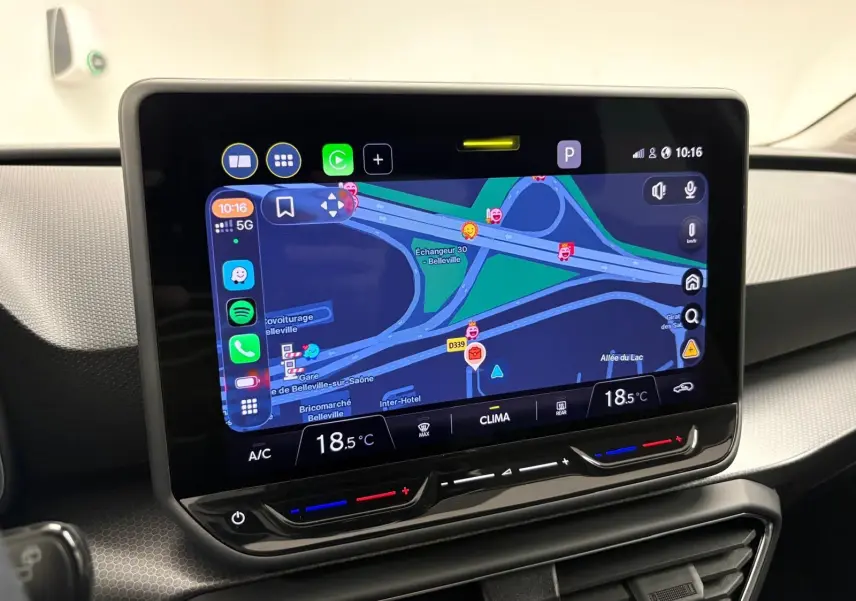Écran tactile central du SEAT LEON 1.5 eTSI Hybrid 2025 affichant la navigation avec commandes climatiques intégrées.