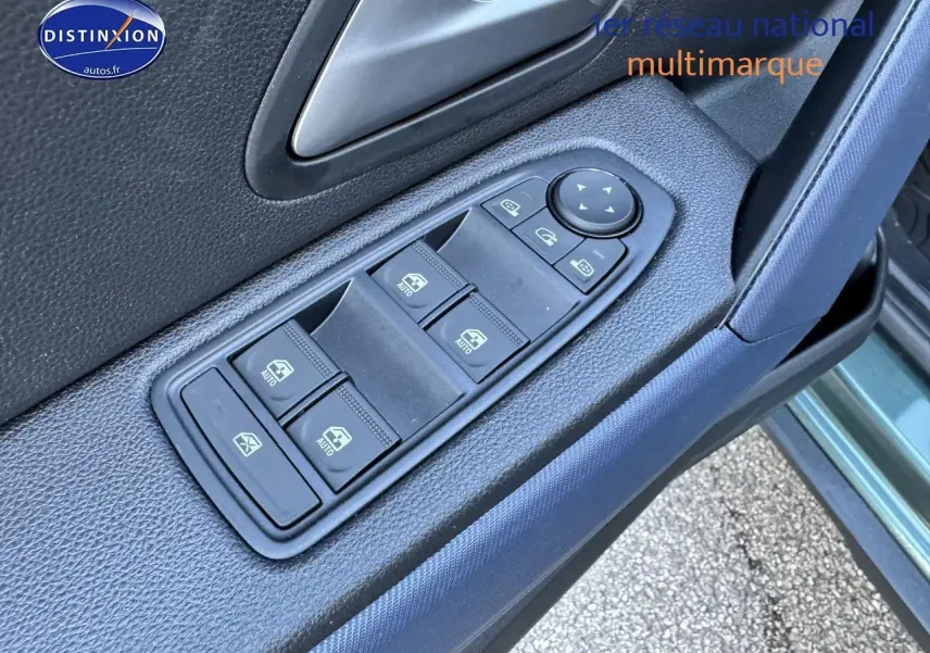 Gros plan sur les commandes des vitres électriques côté conducteur du Dacia Duster vert cèdre 2025.