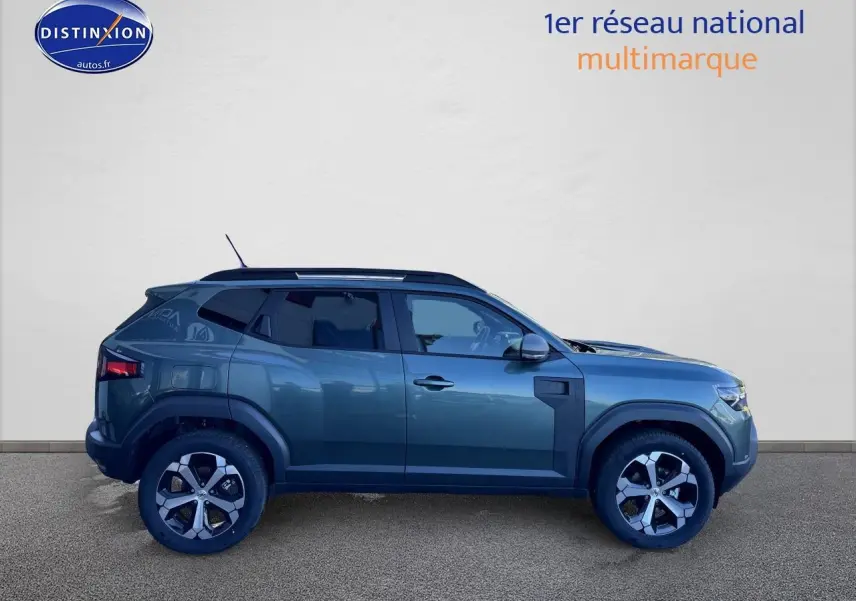 Profil droit d'un Dacia Duster 2025 vert cèdre avec jantes alu et barres de toit visibles sur fond neutre.