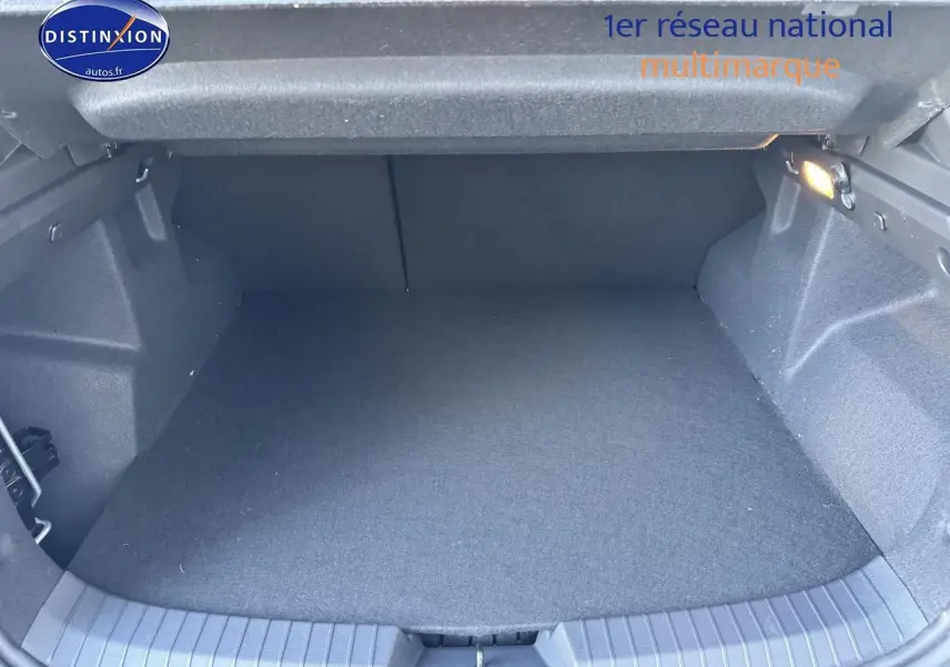 Coffre vide de Dacia Duster 2025 vu de face, intérieur en tissu gris foncé avec éclairage latéral.