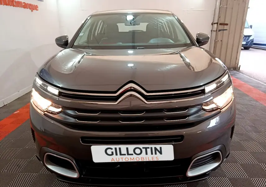 Vue avant d'un Citroën C5 Aircross gris foncé 2020 avec feux allumés et calandre chromée distinctive.