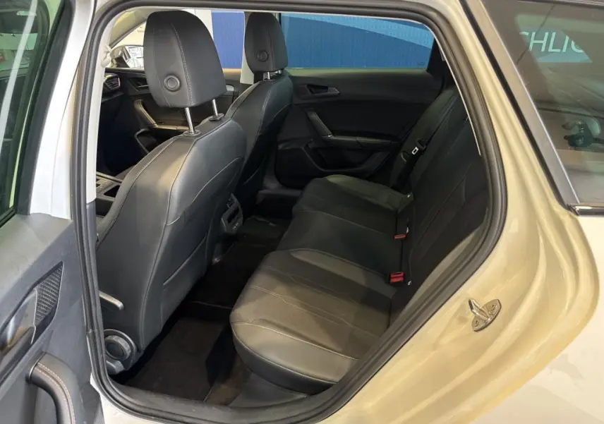 Vue intérieure arrière côté gauche de la CUPRA LEON ST blanche 2024, sièges arrière en cuir noir et finition soignée.