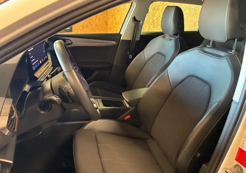 Vue intérieure côté conducteur de la CUPRA LEON ST 2024, sièges noirs en cuir avec surpiqûres contrastées.