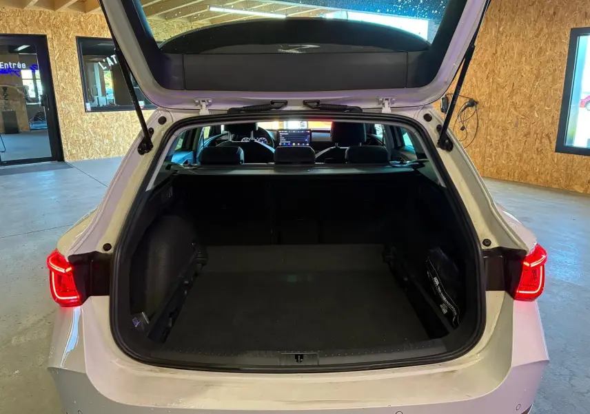 Vue arrière ouverte du coffre d'une CUPRA Leon ST blanche 2024, avec feux arrière allumés en intérieur.