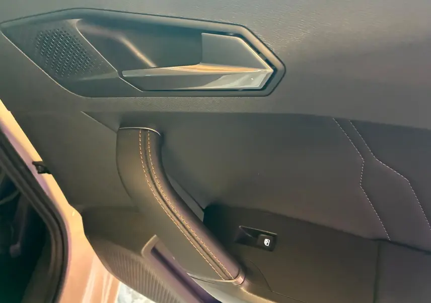 Détail de la poignée intérieure côté gauche d’une CUPRA LEON ST blanche, avec surpiqûres et bouton de lève-vitre.
