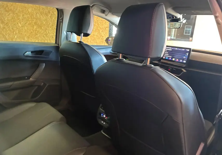 Vue intérieure arrière de la CUPRA Leon ST 2024 avec sièges en cuir noir et écran tactile central visible à l'avant.