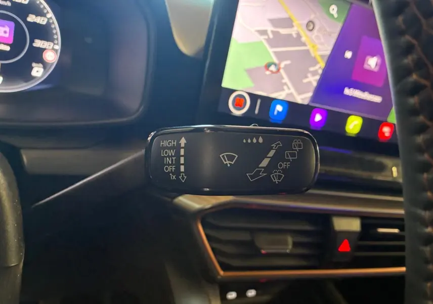 Gros plan sur la commande d’essuie-glace à gauche du volant dans l’habitacle noir du CUPRA LEON ST 2024.