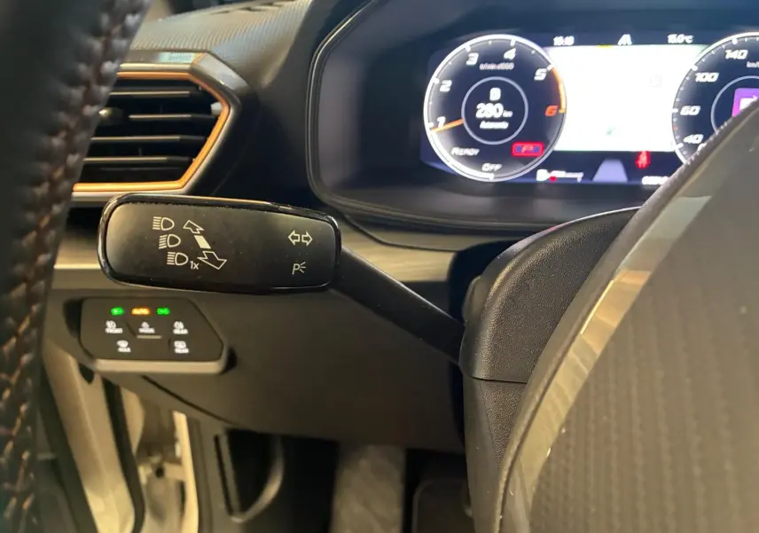 Gros plan sur la manette de clignotants à gauche du volant dans l’habitacle noir du CUPRA LEON ST 2024.