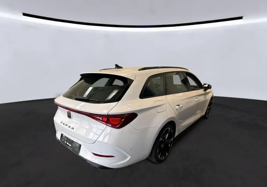 Vue 3/4 arrière droite d'une CUPRA Leon ST blanche 2024 avec toit panoramique et feux arrière LED reliés.