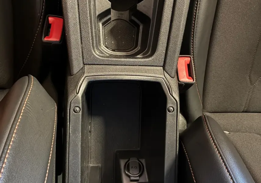 Vue plongeante sur la console centrale noire avec porte-gobelets et prise 12V du CUPRA LEON ST 2024 intérieur.