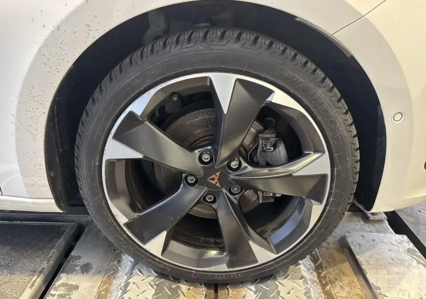 Gros plan sur la roue avant droite d'une CUPRA LEON ST blanche 2024, avec jante alliage noire et argentée au design sportif.