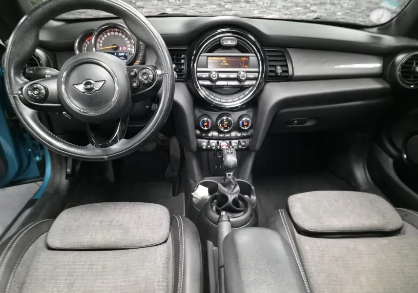 Vue intérieure avant de la MINI Cabriolet bleu, tableau de bord noir avec volant cuir et console centrale équipée.