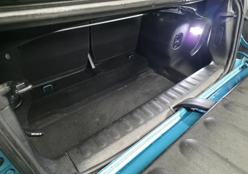 Coffre ouvert d'une MINI Cabriolet bleu 2017, montrant l'espace de chargement avec seuil de porte noir texturé.