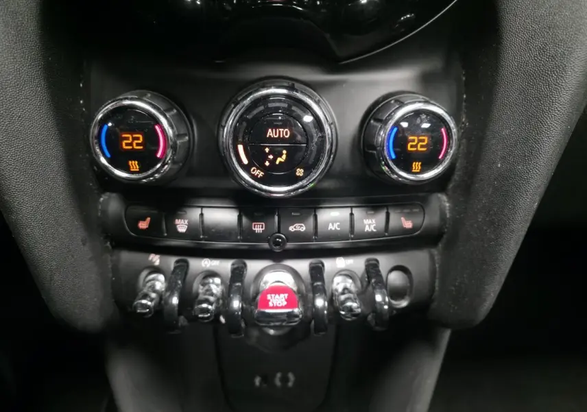 Gros plan sur la console centrale du MINI Cabriolet bleu, affichant la climatisation automatique et le bouton Start/Stop rouge.