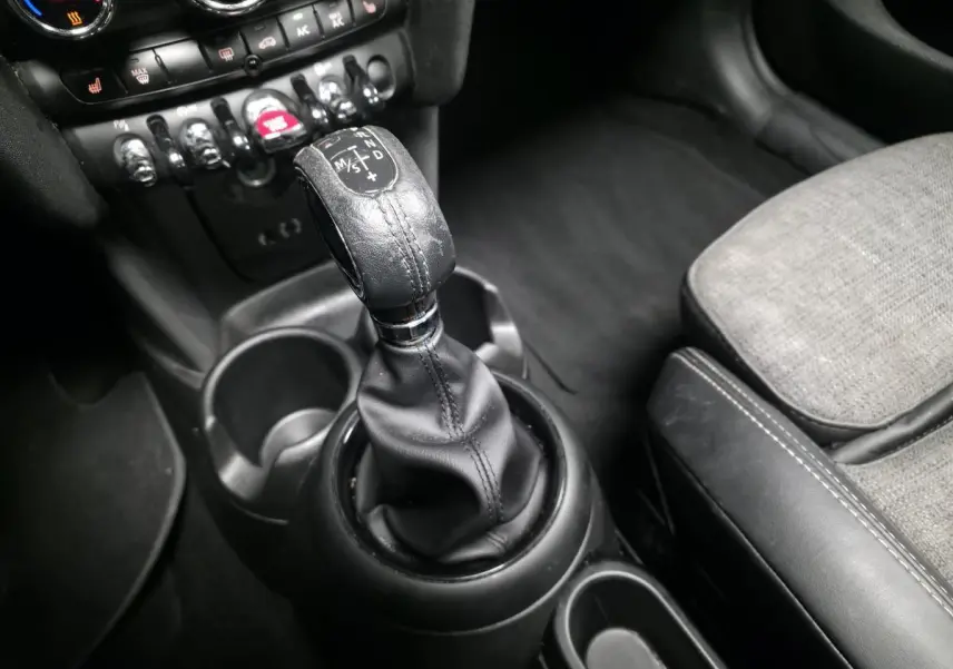 Gros plan sur la console centrale et levier de vitesse cuir noir de la MINI Cabriolet bleu, sièges tissu et cuir gris.
