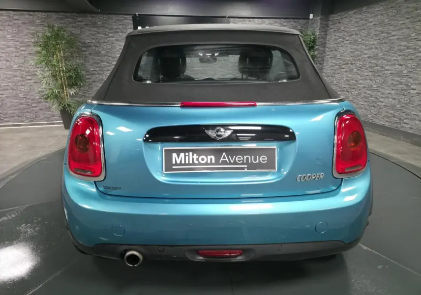 Vue arrière d'une MINI Cabriolet bleu avec capote noire et sortie d'échappement chromée à droite.