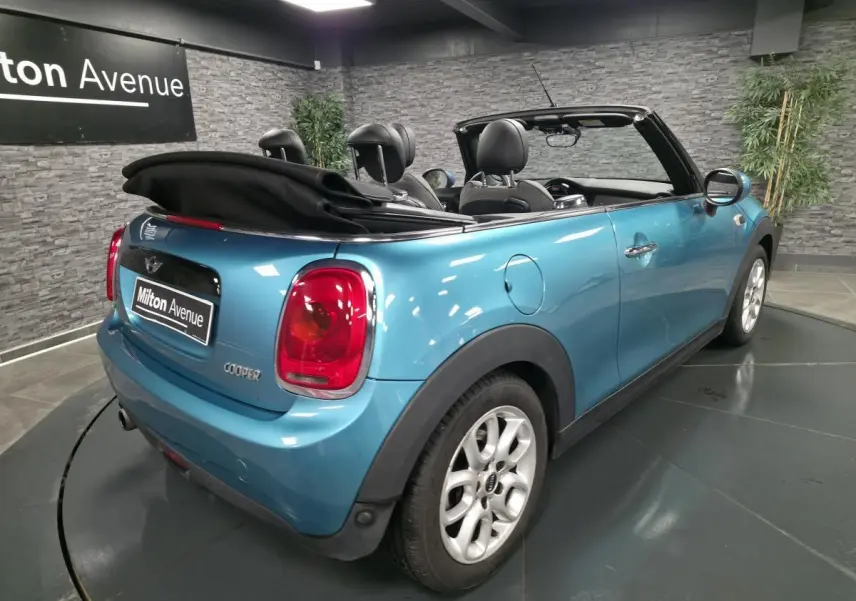 MINI Cabriolet bleu vue 3/4 arrière droit avec capote noire repliée et jantes argentées.