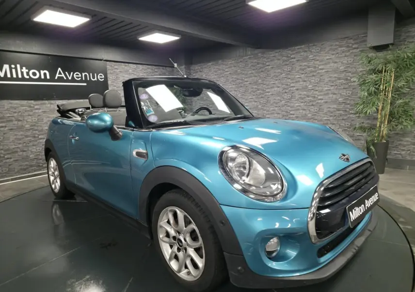 MINI Cabriolet bleu vue 3/4 avant droit, capote noire ouverte et jantes argentées visibles.
