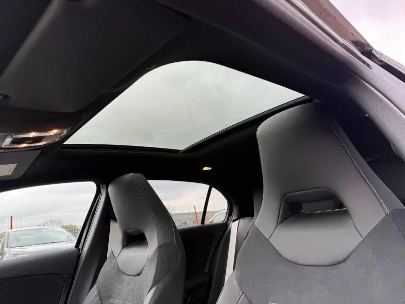 Vue intérieure montrant les sièges sport noirs et le toit ouvrant panoramique d'une Mercedes Classe A gris montagne.