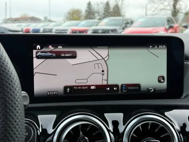 Vue intérieure centrée sur l'écran tactile du GPS de la Mercedes Classe A gris montagne, avec aérateurs ronds chromés visibles.