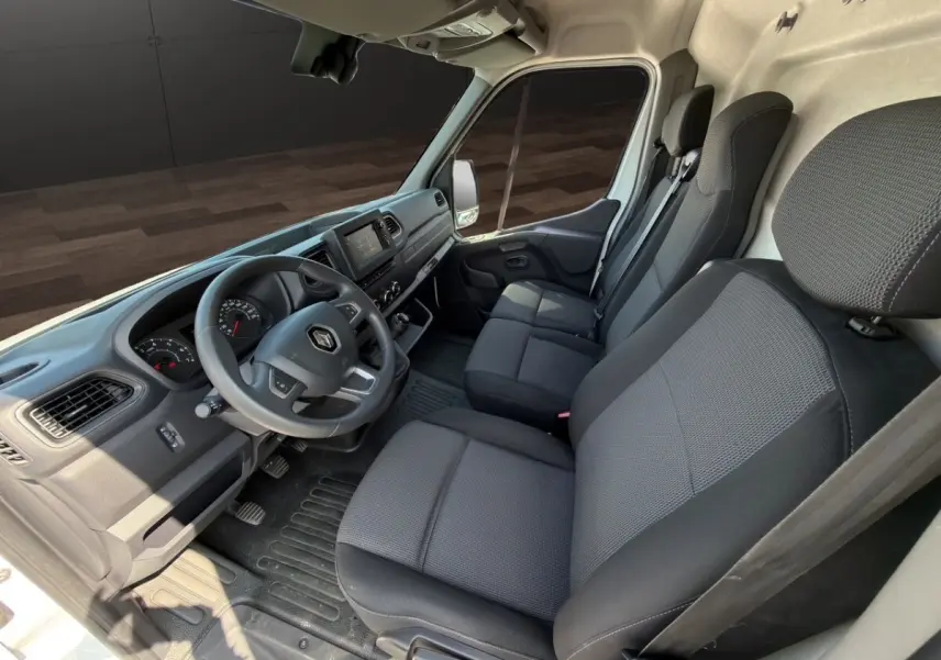 Vue intérieure côté conducteur du Renault Master blanc 2023, montrant le tableau de bord et les sièges noirs.