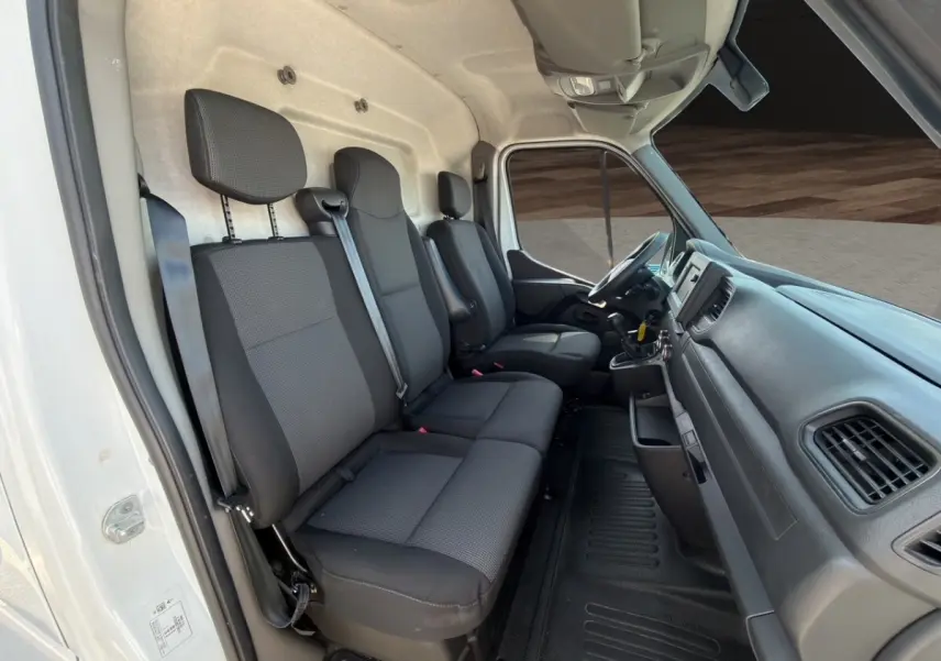Intérieur cabine Renault Master 2023 vu côté gauche, sièges tissu noirs et tableau de bord fonctionnel.