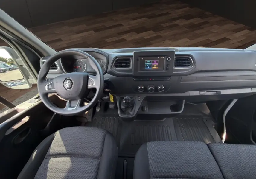 Vue intérieure avant du tableau de bord du Renault Master 2023 avec volant, écran tactile central et sièges gris.