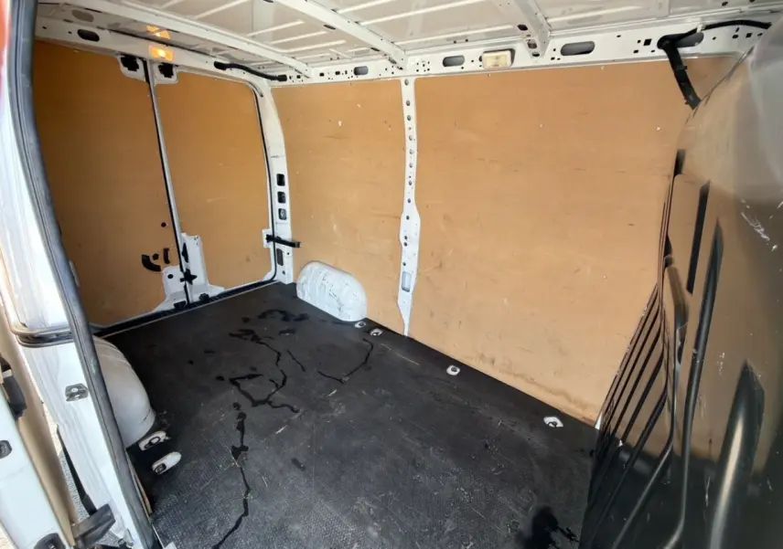 Vue intérieure arrière droite du Renault Master blanc 2023 avec cloison bois et sol noir antidérapant.