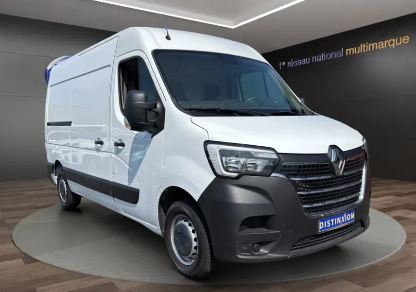 Renault Master blanc en vue 3/4 avant droit, avec calandre noire et jantes acier, sur fond intérieur showroom.